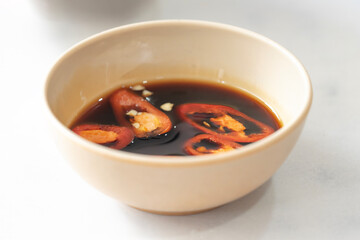 Hot and spicy red chilli in soy sauce. Soy sauce in a bowl isolated. Soy sauce with a few slices of red pepper