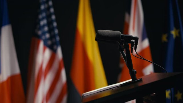 Rostrum with microphone at political summit, briefing room, flags background