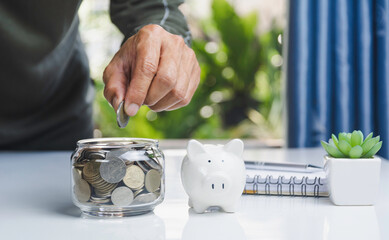 Hand with money coins in clear glass, Business investment growth concept, saving concept, Hand putting coin in clear jar.