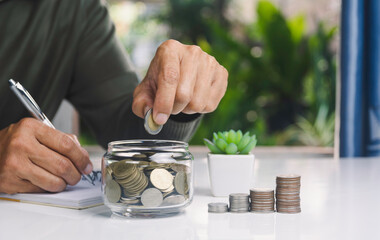 Hand with money coins in clear glass, Business investment growth concept, saving concept, Hand putting coin in clear jar.