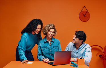 A strong creative team of adults brainstorming with a laptop in an office setting
