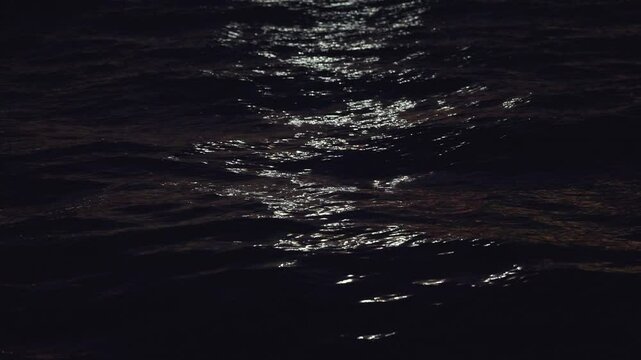 Slow motion view of moonlight glistening across textured sea surface at night, peaceful and atmospheric, natural backdrop soothing serene view