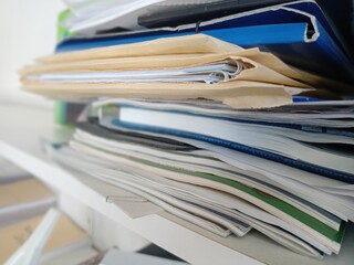 Stack of papers, files, data, books in a shelf in a office drawer.