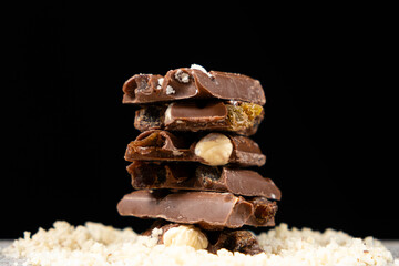 Pieces of milk nut chocolate on a black background.