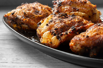 Fried chicken with hot thai bbq seasoning on a black stoneware dish. On wooden background