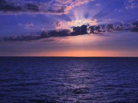 Sunset clouds sky over dark blue sea. 