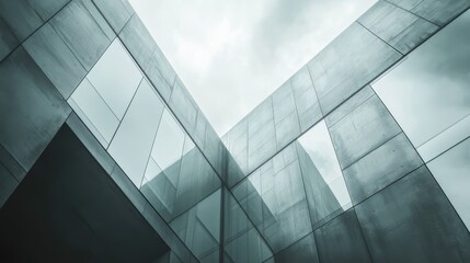 Obraz premium Modern architecture glass and concrete building reflecting cloudy sky