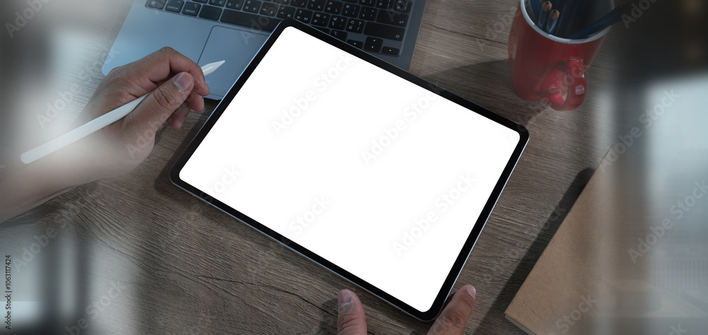 Poster man using digital tablet with blank white screen mock up on a table at office