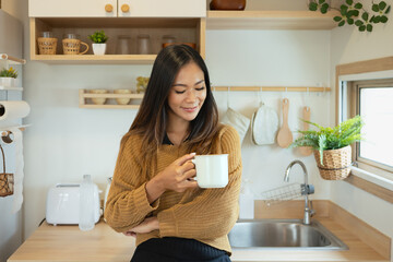 Happy young woman having a first morning coffee in her Minimalist kitchen