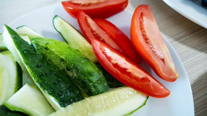 Freshly sliced cucumbers and tomatoes on a plate symbolize healthy eating habits and summer picnic themes