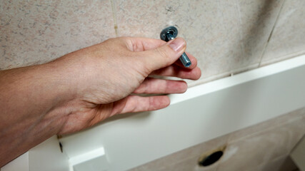 A person installs a screw into a tiled wall, illustrating home repair and DIY problem-solving