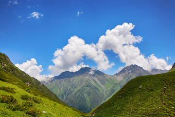 Idyllic summer landscape with hiking trail in the mountains with beautiful fresh green mountain pastures.