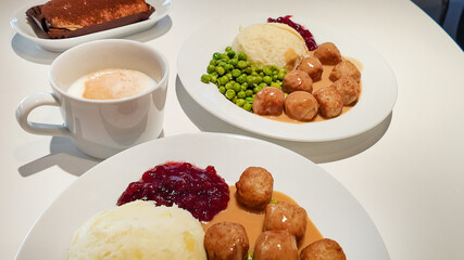 Two plates of Swedish meatballs with mashed potatoes, gravy, lingonberry sauce, and peas, ideal for celebrating Swedish culture