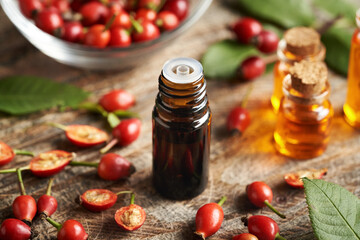 Rosehip seed oil with fresh rose hips on a table