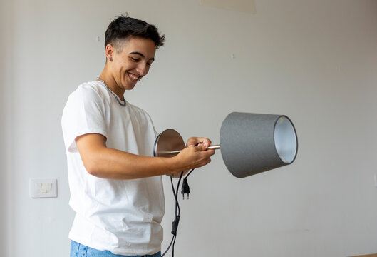 Trans man smiles while setting up lamp in new apartment