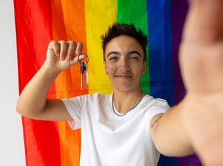 Proud trans man with new home keys against a pride flag