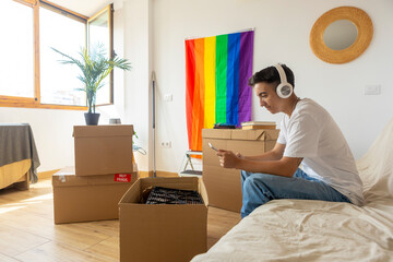 Trans man unpacking boxes in new home with pride flag