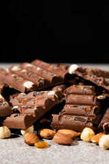 Lots of chocolate bars with nuts and raisins on a black background