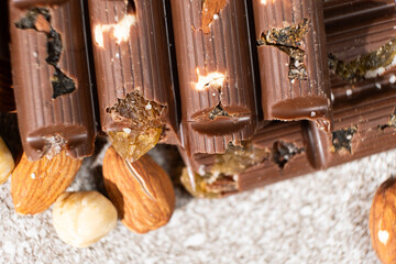 Broken chocolate pieces with nuts and raisins on a stone background top view