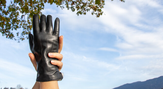 Eine Hand umarmt eine Hand im schwarzen Leder Handschuh, Himmel, Breitbildformat