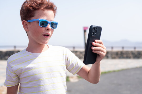 Young boy reacts to smartphone content on sunny day
