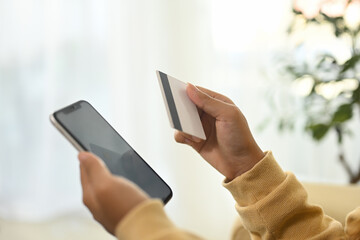 Close up of a woman using her smartphone and credit card for online purchases