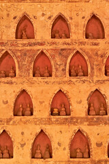 Many small, miniature buddha figurines, sculptures, statues are displayed in the cloister wall of...