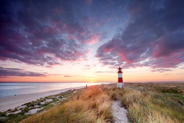Lighthouse on the island of Sylt in the dunes by the sea at a wonderful sunrise