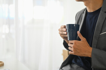 Cropped shot of businessman with a mug of coffee relaxing in the office