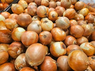 Close-up of a heap of onions at a local fruit market, emphasizing the rich color and freshness of the produce, ideal for agricultural and culinary themes