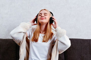 A woman relaxes on the sofa, enjoying music through her headphones. An attractive young girl takes...