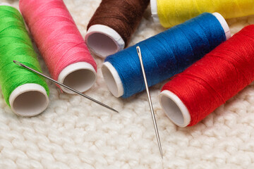 Colored spools of thread and sewing needles on sewing close-up