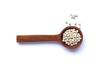 Dried white pepper seeds in a wooden spoon and spread isolated on white background top view flat lay