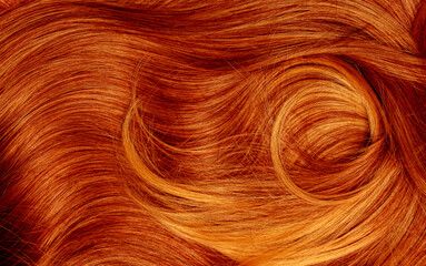 Naklejka premium Red hair close-up as a background. Women's long orange hair. Beautifully styled wavy shiny curls. Hair coloring bright shades. Hairdressing procedures, extension.