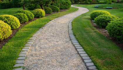 Obraz premium Winding stone and gravel path cutting through landscaped lawn, low shrubs and plants. Natural scene