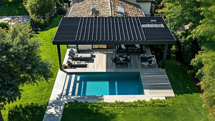An aerial view of a modern home with a pool, patio, and pergola