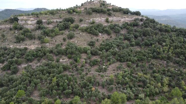 Vista a&eacute;rea de un castillo en ruinas, campos agr&iacute;colas, casas dispersas y un peque&ntilde;o pueblo con gente haciendo trekking, Castillo de Llu&ccedil;&agrave;, Osona