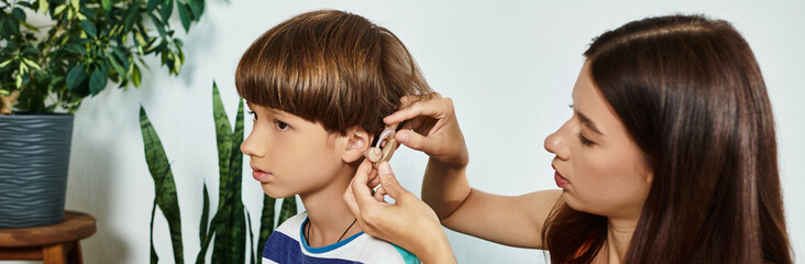 A mother lovingly assists her young son with his hearing aid in a nurturing environment.