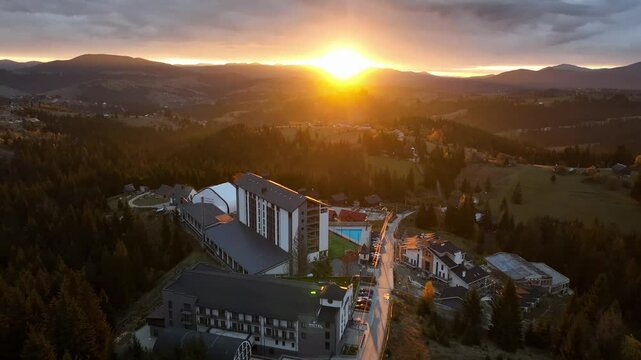 The first light of sunrise spills over the Carpathian region, bathing the landscape in a delicate, golden hue. The hotel hub nestles quietly in the early morning calm. October, 2024.