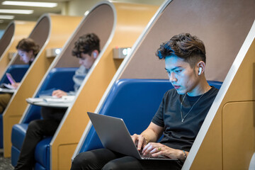 University student working on laptop in modern study pods,