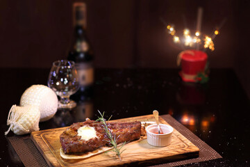 Christmas steak by candlelight. Christmas atmosphere and the mood to eat delicious steaks. Beef steak on a wooden board. Christmas table and steak.