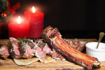 Christmas steak by candlelight. Christmas atmosphere and the mood to eat delicious steaks. Beef steak on a wooden board. Christmas table and steak.