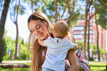 A woman is holding a baby in a park