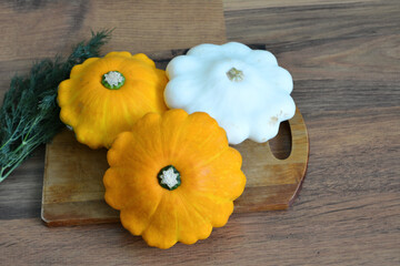 three pattypan squashes on a wooden cutting board top view