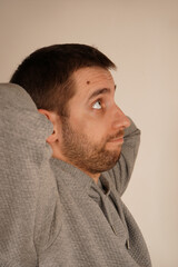 Obraz premium Face with satisfaction. Crossed hands over head. Young guy standing in front of camera with neutral background. Male looking at camera front view. Man in casual clothes. Handsome man.