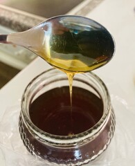 Natural wildflower honey dripping from the teaspoon into the jar