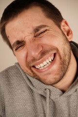 Obraz premium Cheerful, happy enthusiastic man laughing. Grinning joyfully, Portrait of pleased positive male laughs joyfully, expresses happiness, stands against grey background. Happy amazed satisfied young man.