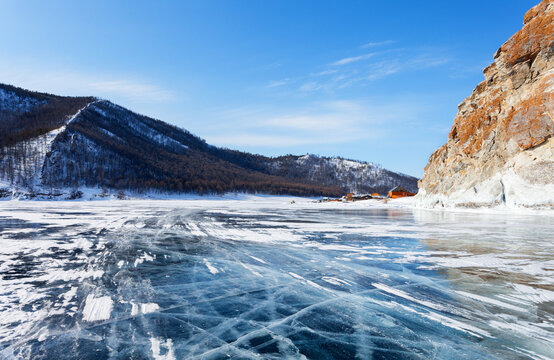 Baikal Lake on a sunny winter day. View from the ice road to the village of Uzury near the rocky shore of Olkhon Island. Winter ice travels and adventures