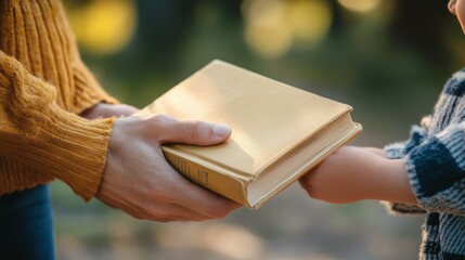 Hand of adult giving a book to a child