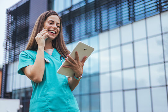 Smiling Nurse Using Tablet and Phone Outside Hospital Building